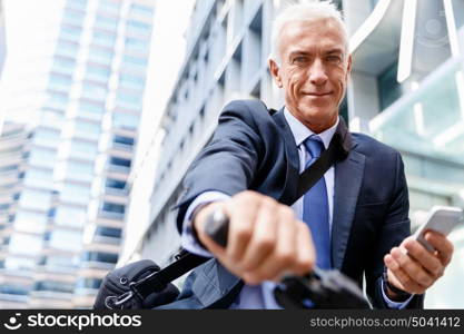 Successful businessman riding bicycle. Successful businessman in suit riding bicycle and holding mobile phone