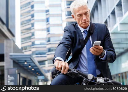 Successful businessman riding bicycle. Successful businessman in suit riding bicycle and holding mobile phone