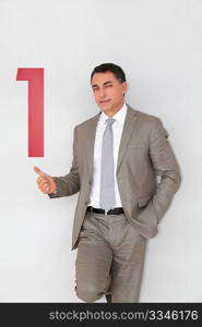 Successful businessman showing number one painted on wall