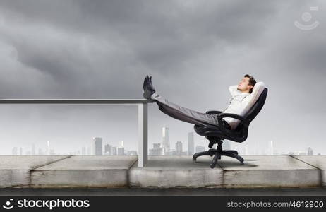 Successful businessman. Young businessman sitting in chair with legs on table