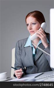 Successful businesswoman calling on the phone at office, having coffee