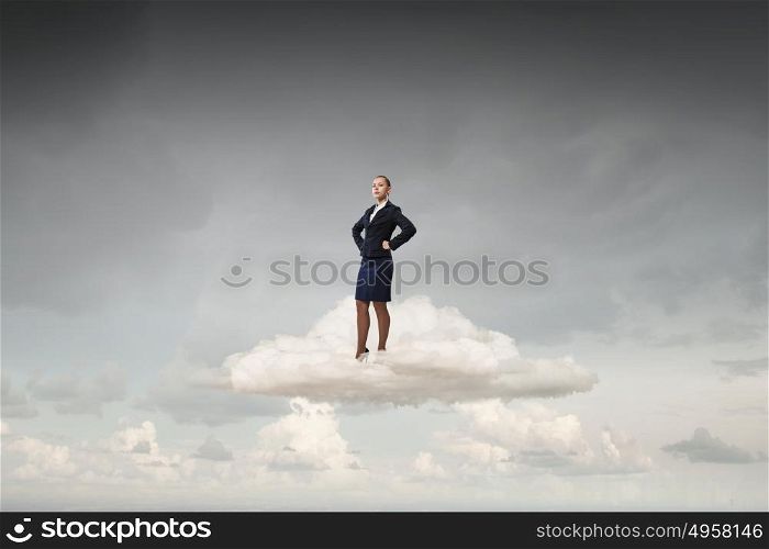 Successful businesswoman on cloud. Young confident businesswoman with hands on waist