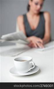 Successful businesswoman read newspaper at office, focus on morning coffee