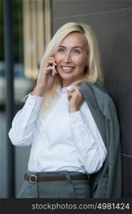 Successful businesswoman talking on cellphone outdoor. City business woman working.