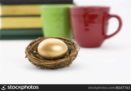 Successful, collaborative investment reflected in two coffee mugs, red and green, and books combined with selective focus on gold nest egg. Education, due diligence. and smart, winning strategy reflected in symbols.