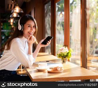 Successful female young adult asian freelancer working in cafe using her mobile phone and coffee breakfast set.