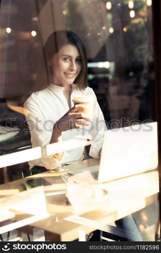 Successful female young adult asian freelancer working in cafe with laptop and coffee cup.