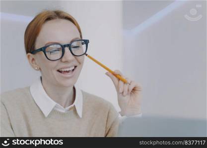 Successful girl is studying online. Happy student holding pencil and taking notes, smiling at camera. Remote study or work concept. Young european businesswoman or employee in office.. Girl is studying online. Happy student holding pencil and taking notes, smiling at camera.