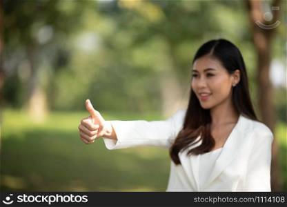 successful girl pointing thumb up; portrait of cheerful smiling woman pointing up approving, yes, ok, good