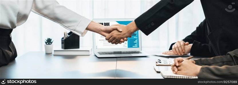 Successful job interview at business office end with handshake. Hired candidate seal deal with HR team recruiter by handshaking with laptop display digital resume in background. Panorama shot. Prodigy. Successful job interview at business office end with handshake. Prodigy