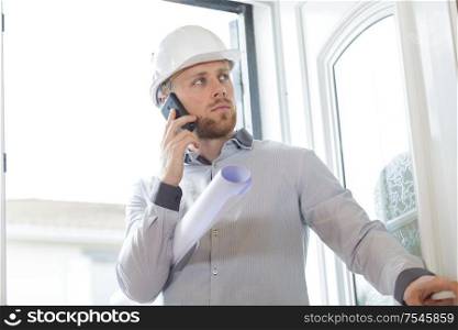 successful male architect in helmet talking mobile phone
