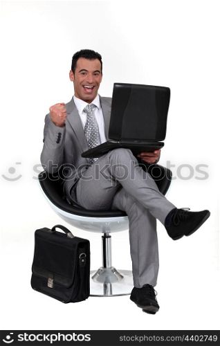 Successful man sat in chair with laptop