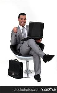Successful man sat in chair with laptop