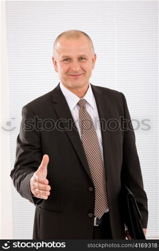 Successful mature executive businessman giving handshake close deal portrait