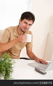 Successful modern businessman with cup of coffee sitting at the office