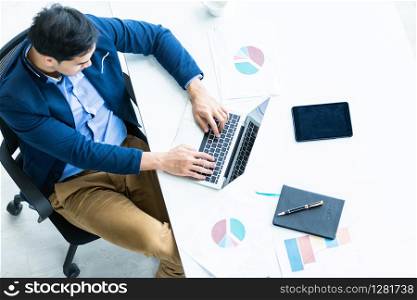 Successful of asian young businessman working with hand typing keyboard on laptop computer, tablet with blank touch screen isolated and Pen on notebook on White wooden table background in office