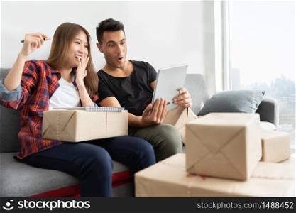 Successful of Young couple are celebrating with profits of their small business online. Male and Female are looking to digital tablet computer at the house together. Achieving goals.