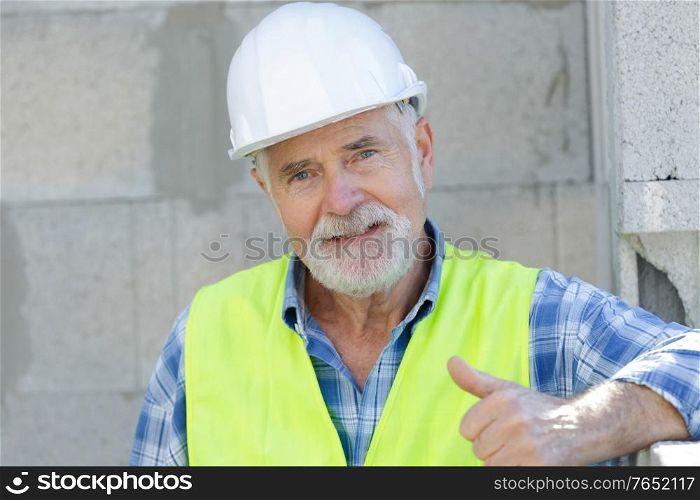 successful senior citizen as craftsman holding thumbs up
