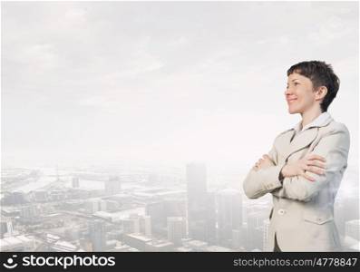 Successful smiling businesswoman. Confident businesswoman with arms crossed on chest on modern city background