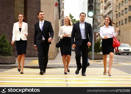 Successful Team of five business people confidently striding along the summer street