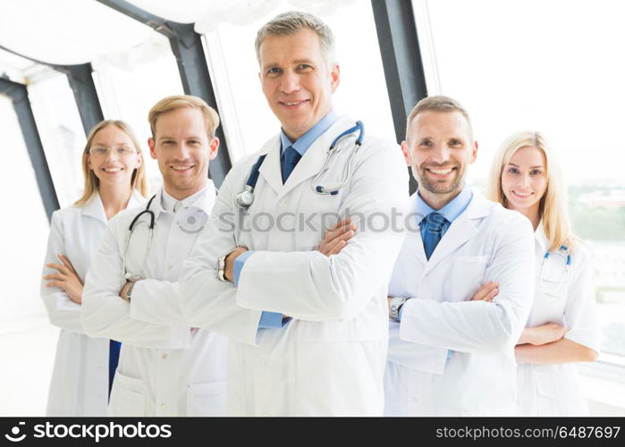 Successful team of medical doctors. Successful team of medical doctors are looking at camera and smiling while standing in hospital with arms crossed