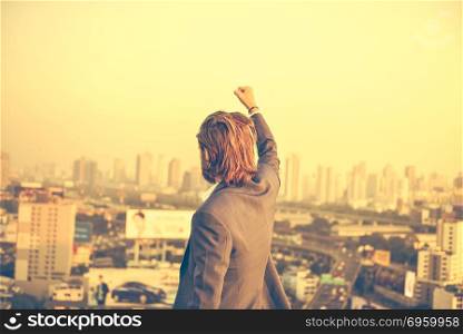 Successful Western businessman with hands up looking at the city. Successful Western businessman with hands up looking at the city at sunset. Successful Western businessman with hands up looking at the city at sunset