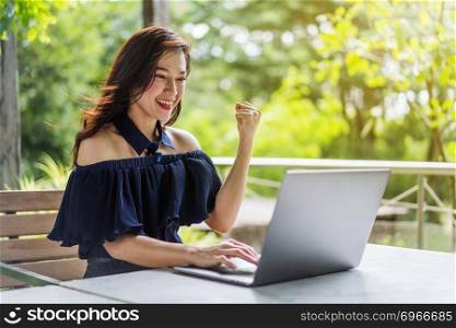 successful woman using laptop computer with arms raised