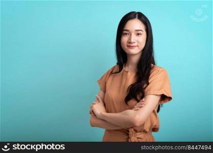 Successful young beautiful asian businesswoman cross arms confident and looking at camera smiling isolated on blue background