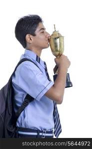 Successful young boy kissing trophy against white background