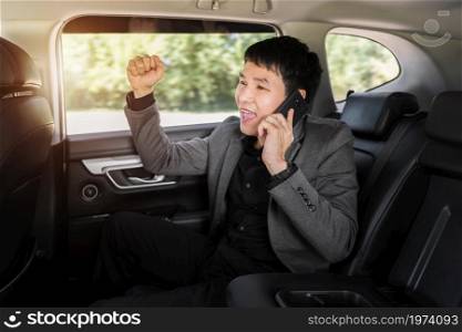 successful young business man talking on a mobile phone while sitting in the back seat of car