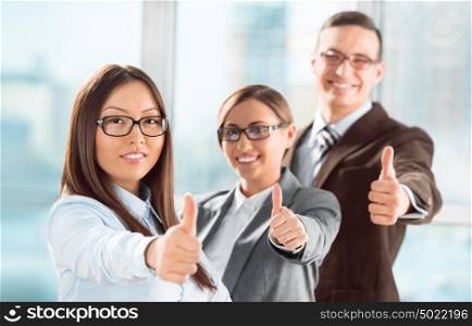 Successful young business people showing thumbs up sign