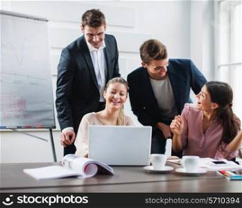 Successful young business people using laptop at desk in office