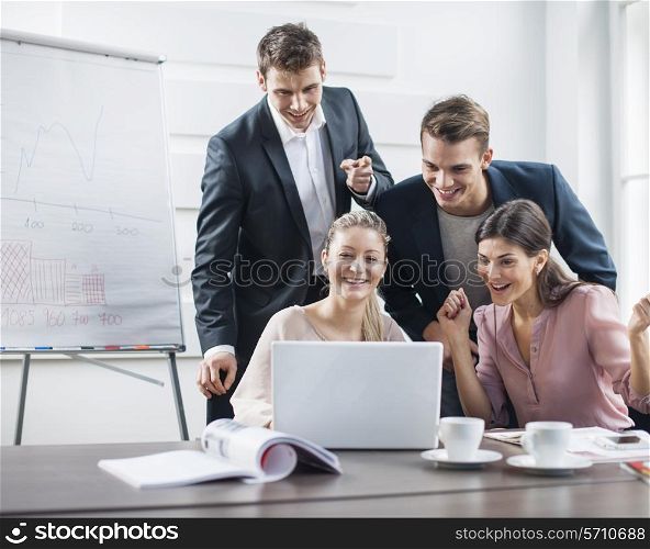 Successful young business people using laptop in meeting