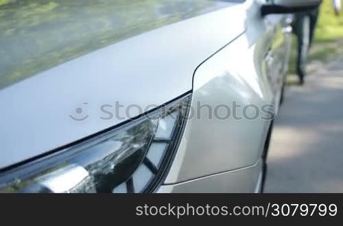 Successful young businessman in stylish clothes getting into parked luxury auto while travelling by car in countryside. Selective focus. Confident business executive in formal wear openning car&acute;s door and getting into vehicle. Slo mo. Stabilized shot