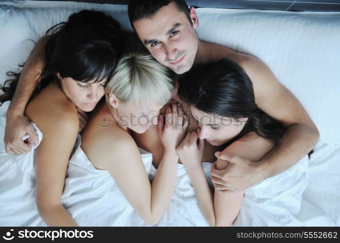 successful Young handsome man lying in bed with three sleeping girls