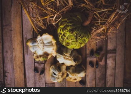 Sugar apple - cherimoya ( Annona scaly ) on the board with hay with bones and a plate