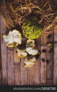 Sugar apple - cherimoya ( Annona scaly ) on the board with hay with bones and a plate
