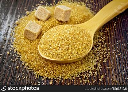 Sugar brown granulated in a spoon and cubes on a wooden board background