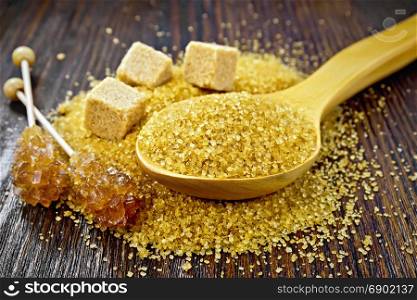 Sugar brown granulated in a spoon, crystal on a stick and cubes on a wooden board background