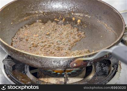 sugar caramelizing in a frying pan at gas stove in kitchen