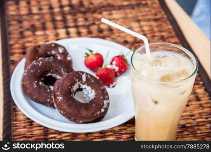 Sugar chocolate donuts and fresh strawberries and ice coffee