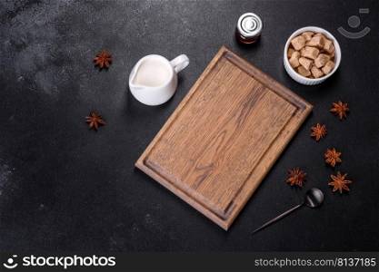 Sugar, cinnamon and other spices on a wooden cutting board on a dark concrete background. Sugar, cinnamon and other spices on a wooden cutting board