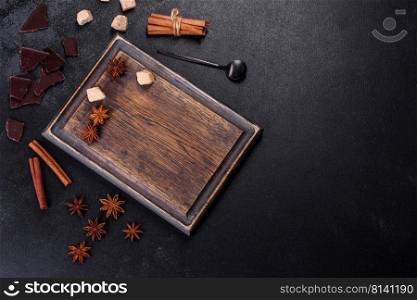 Sugar, cinnamon and other spices on a wooden cutting board on a dark concrete background. Sugar, cinnamon and other spices on a wooden cutting board