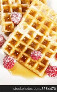 sugar covered raspberries on waffles with syrup. sugar covered raspberries on waffles with syrup from top on white background