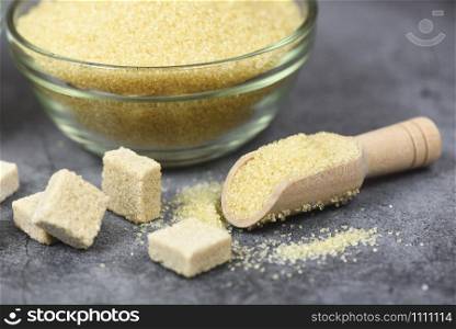 sugar cubes and heap of brown sugar on bowl and wooden scoop on table background