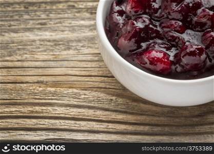 sugar free cranberry sauce with addition of blueberry - sidedish bowl against grained wood