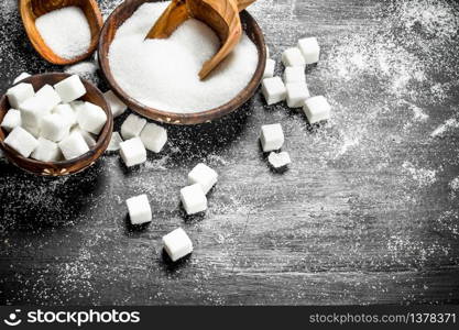 Sugar in a bowl with a scoop. On the black chalkboard.. Sugar in a bowl with a scoop.