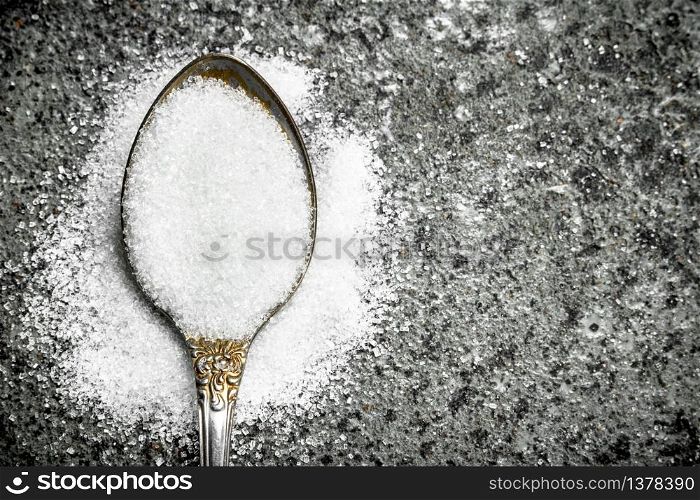 Sugar in a teaspoon. On a rustic background.. Sugar in a teaspoon.