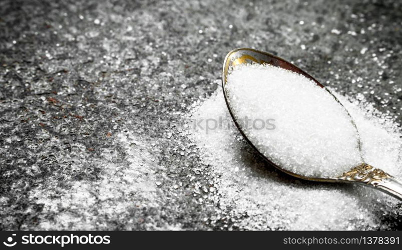 Sugar in a teaspoon. On a rustic background.. Sugar in a teaspoon.