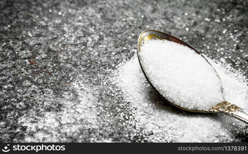 Sugar in a teaspoon. On a rustic background.. Sugar in a teaspoon.